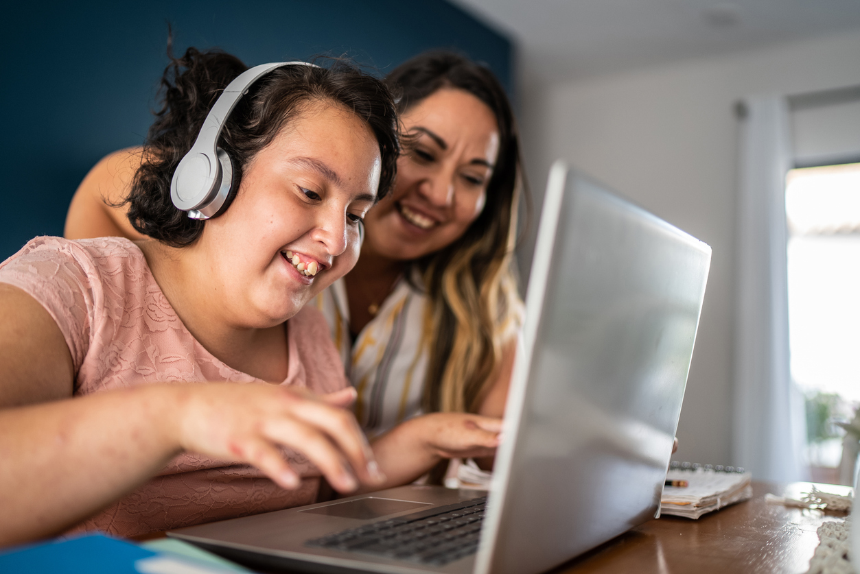 Young girl with autism wearing a headset while studying using AI on laptop at home.