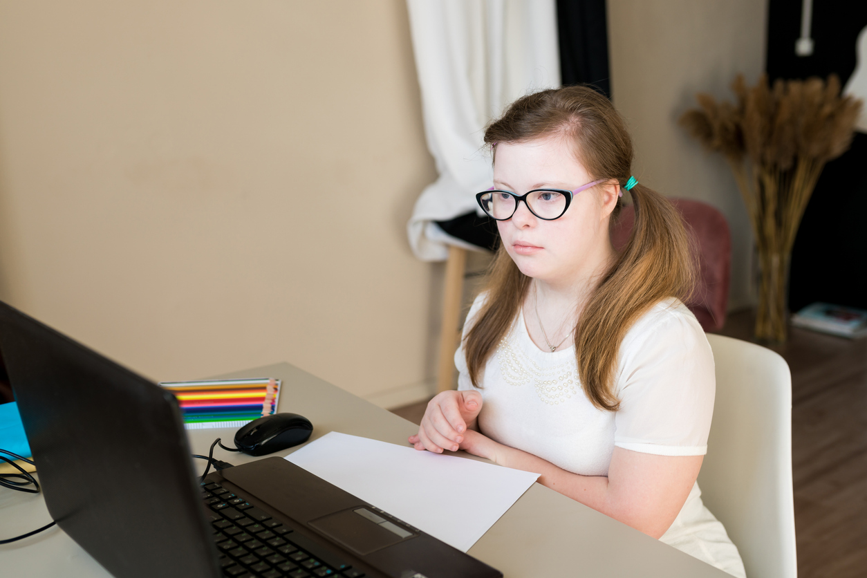 Young girl looking at a laptop showing how AI helps children with autism.