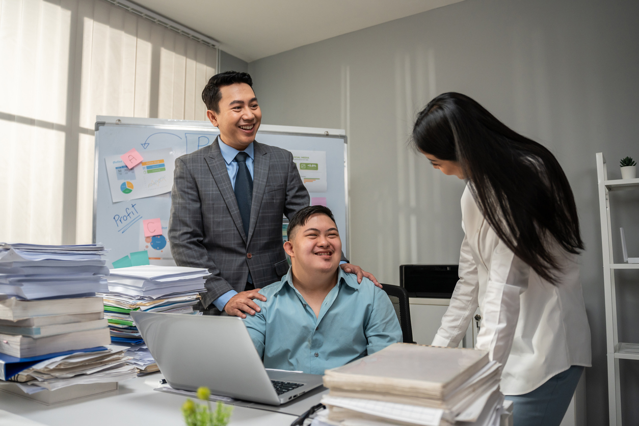 Young businessman working with a female employee and an adult with autism in an office.