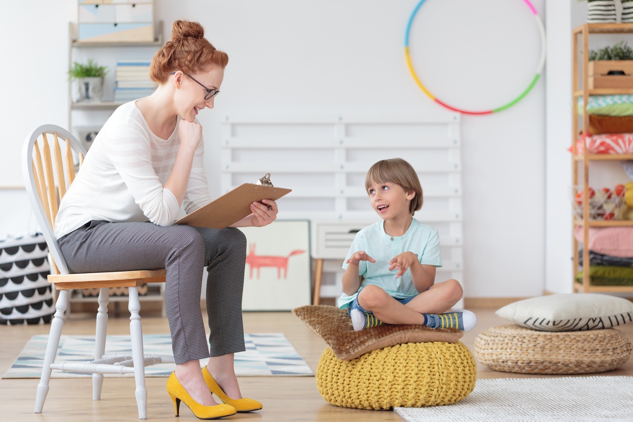 Woman holding a notepad while talking to a child in a health center.